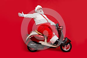 Profile side view portrait of nice bearded glad cheerful cheery funny funky Santa riding moped hurry up having fun holly