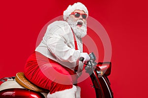 Profile side view portrait of nice bearded positive cheerful funny funky Santa riding moped hurry up winter season