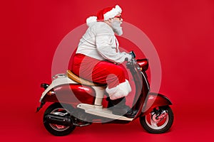 Profile side view portrait of nice bearded serious confident Santa father riding motor bike delivering fairy tale dream