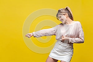 Profile side view of positive assertive young woman with fair hair in casual beige blouse, isolated on yellow background