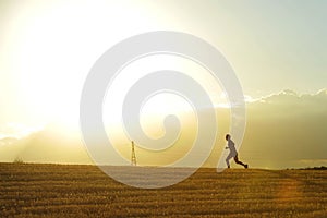 Profile silhouette of young man running in countryside training cross country jogging discipline in summer sunset