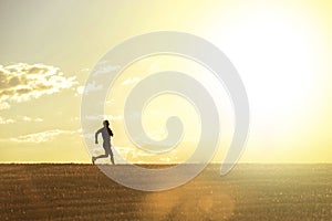 Profile silhouette of young man running in countryside training cross country jogging discipline in summer sunset