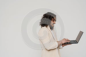 Profile of smiling hispanic man working on laptop isolated over white background