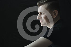 Profile of smiling young man portrait in low-key lighting