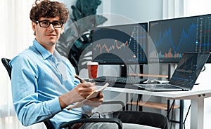 Profile of smiling young stock trader looking at camera holding paper. Gusher.