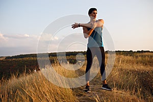Profile of a strong, muscular, runner man in sportswear, isolated on a beautiful summer sunset landscape background.