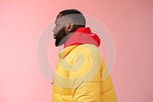 Profile studio shot bearded young 25s african guy in yellow jacket red hoodie look left normal unbothered relaxed