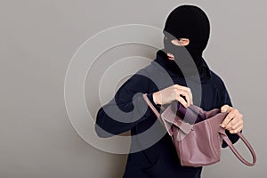 Profile of a thief guy with a masked face, a burglar stole a purse and a woman`s handbag looking back, afraid to be caught, copy