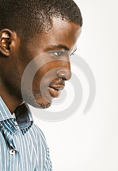 Profile view of African American man in a blue striped shirt. Close-up portrait of an attractive dark-skinned guy