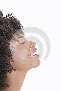 Profile view of an African American woman smiling with eyes closed against gray background