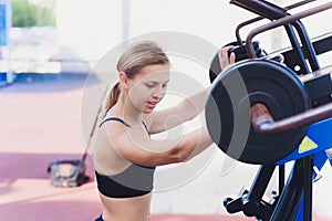 Profile view of a female athlete doing some tricep dips on a park bench.