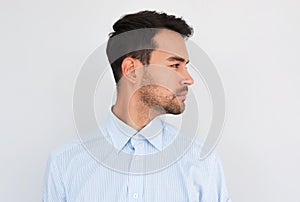 Profile view of handsome young handsome male wearing light blue shirt looking to the copy space for advertisement, posing on white