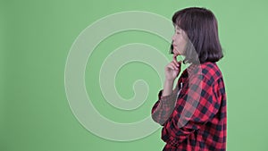 Profile view of happy Asian hipster woman thinking