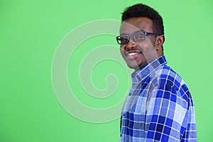 Profile view of happy young African hipster man smiling and looking at camera