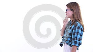 Profile view of happy young Asian hipster woman thinking