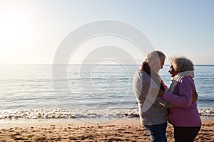 Profile View Of Loving Retired Couple Hugging Standing By Sea On Winter Beach Vacation