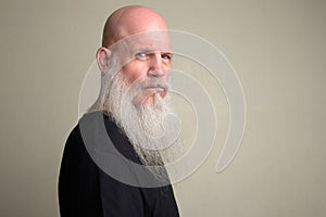 Profile view of mature bald man with long gray beard looking at camera