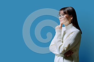 Profile view of middle aged happy woman, blue background, copy space