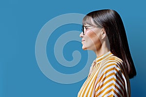 Profile view of middle aged smiling woman, blue background, copy space