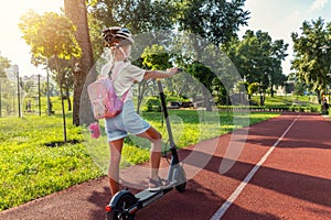 Profile view portrait of cute blond little caucasian school girl wear helmet enjoy having fun riding electric scooter