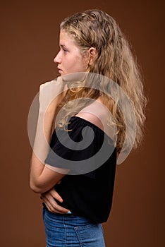 Profile view portrait of young beautiful blonde teenage girl thinking