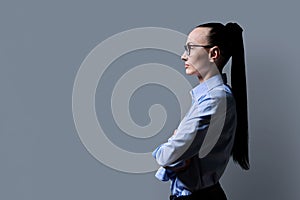 Profile view of 30s serious business woman, gray background, copy space