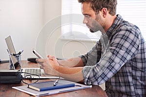 Profile view of white man using his cellphone at desk