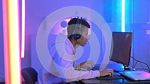 Profile view of young gammer in headphones playing in online shooter