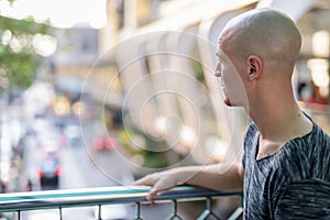 Profile view of young handsome bald man thinking in city