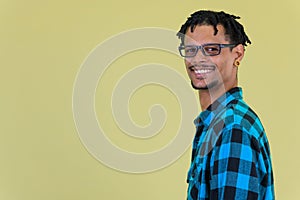 Profile view of young happy African hipster man smiling and looking at camera