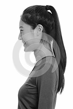 Profile view of young happy Asian teenage girl smiling