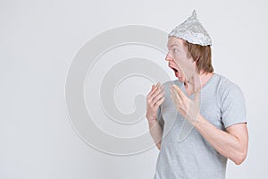 Profile view of young man with tinfoil hat looking shocked