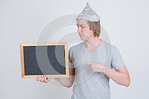 Profile view of young man with tinfoil hat pointing at blackboard