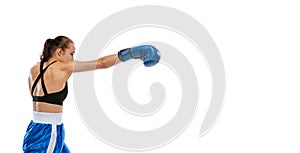 Profile view of young sportive girl, professional boxer practicing in boxing gloves isolated on white studio background