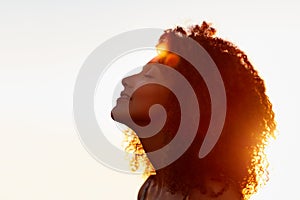 Profile of a woman with afro silhoutted against evening sun