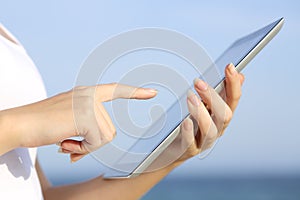 Profile of a woman hands holding and browsing a digital tablet on the beach photo