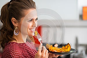 Profile of woman holding bite of roasted pumpkin on a fork