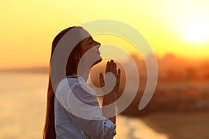 Profile of a woman praying at sunset photo