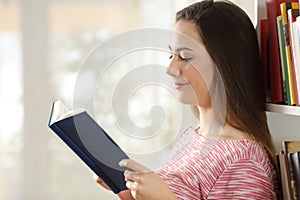 Profile of a woman reading a book at home