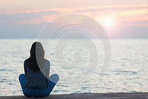 Profile of a woman silhouette watching sun on the beach