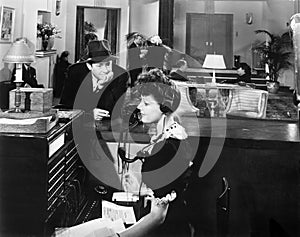 Profile of a woman working on the telephone switchboard with a man looking at her