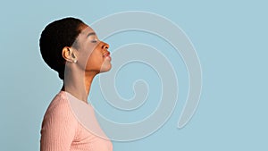 Profile Of Young African-American Woman Standing With Closed Eyes Over Blue Background