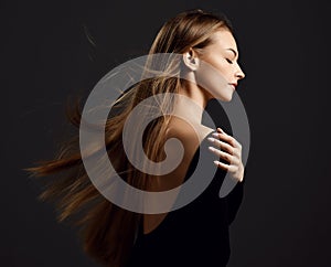 Profile of young beautiful woman with long silky straight flying hair in black body with eyes closed