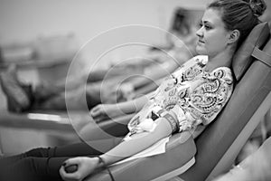 Profile of young lady sitting in medical chair and donating bood