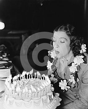 Profile of a young woman blowing off candles on a birthday cake