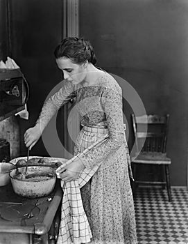 Profile of a young woman cooking food in the kitchen