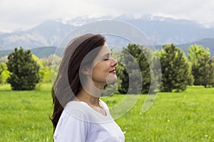 Profile of young woman with eyes closed breathing fresh air in the mountains