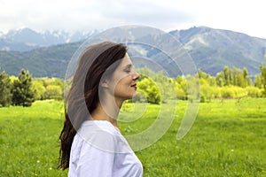 Profile of young woman with eyes closed breathing fresh air in the mountains