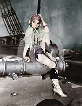 Profile of a young woman sitting on a cannon and thinking