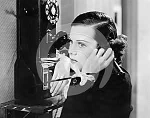 Profile of a young woman talking on a payphone